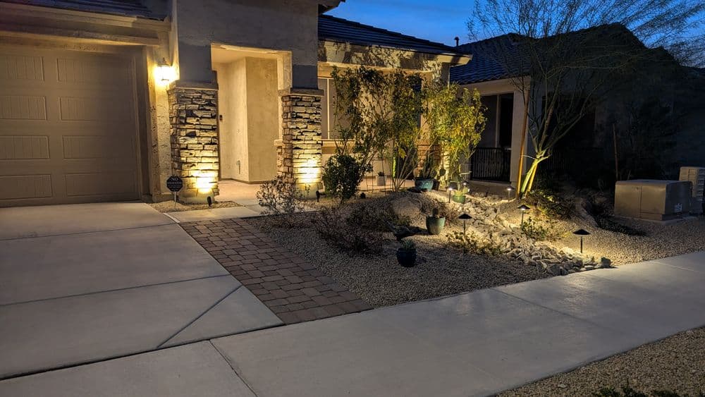 Well-lit desert landscaping at dusk with stone accents and pathway lighting.