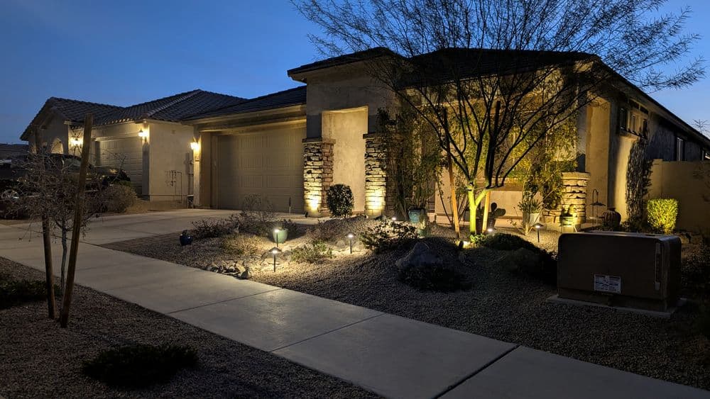 Modern home exterior at dusk, featuring landscape lighting and desert landscaping details.