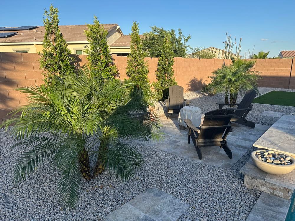 Desert backyard with palm trees, gravel, and patio chairs for outdoor relaxation.